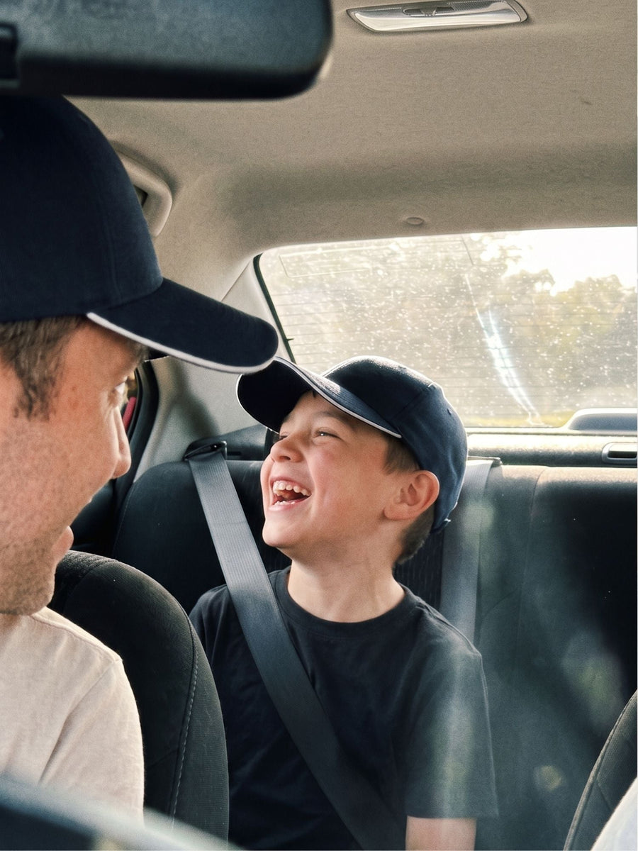 Navy — father and son in matching navy Kindred Caps laughing in the car
